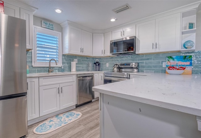 kitchen with tasteful backsplash, visible vents, stainless steel appliances, white cabinetry, and a sink