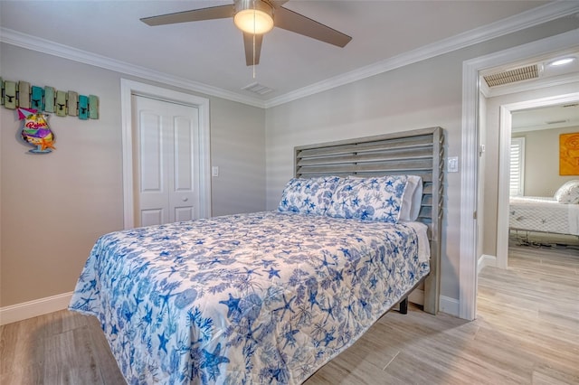 bedroom featuring visible vents, wood finished floors, baseboards, and ornamental molding