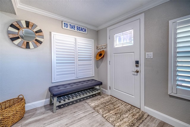 entrance foyer with crown molding, baseboards, wood finished floors, a textured wall, and a textured ceiling