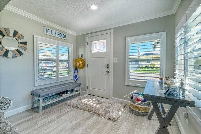 entryway featuring plenty of natural light, a textured ceiling, wood finished floors, and ornamental molding