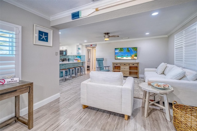 living room with a ceiling fan, baseboards, recessed lighting, ornamental molding, and light wood-type flooring