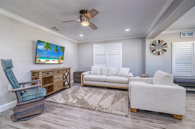 living area featuring visible vents, baseboards, ceiling fan, ornamental molding, and wood finished floors