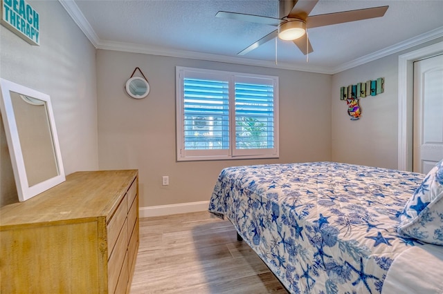 bedroom featuring light wood finished floors, baseboards, ornamental molding, a textured ceiling, and a ceiling fan