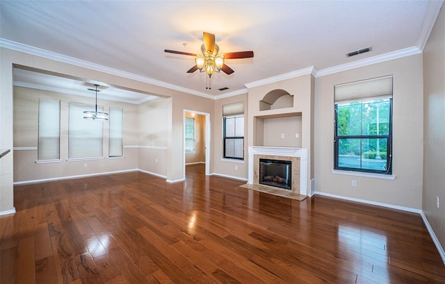 unfurnished living room featuring crown molding, dark wood-type flooring, a tile fireplace, and ceiling fan