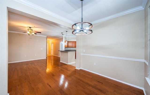 interior space featuring ornamental molding, wood-type flooring, and ceiling fan with notable chandelier