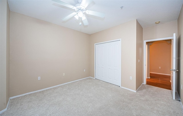 unfurnished bedroom with light carpet, a closet, and ceiling fan