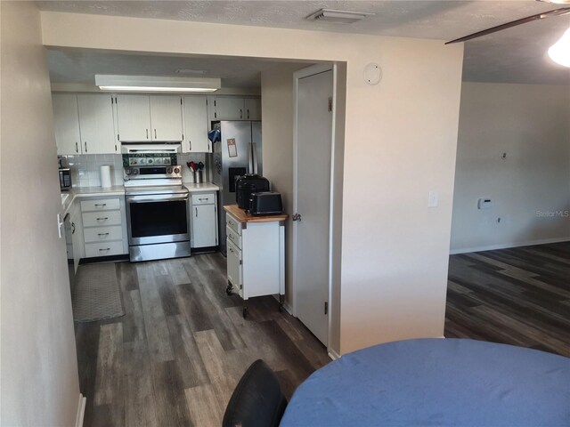 kitchen featuring dark wood-type flooring, appliances with stainless steel finishes, a textured ceiling, and backsplash