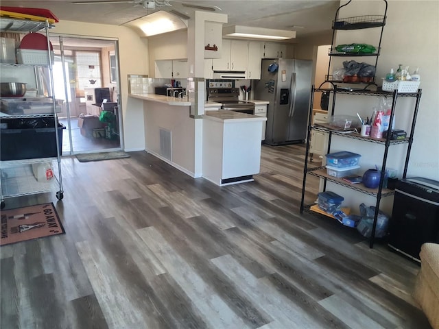 kitchen with appliances with stainless steel finishes, backsplash, white cabinets, dark hardwood / wood-style flooring, and kitchen peninsula