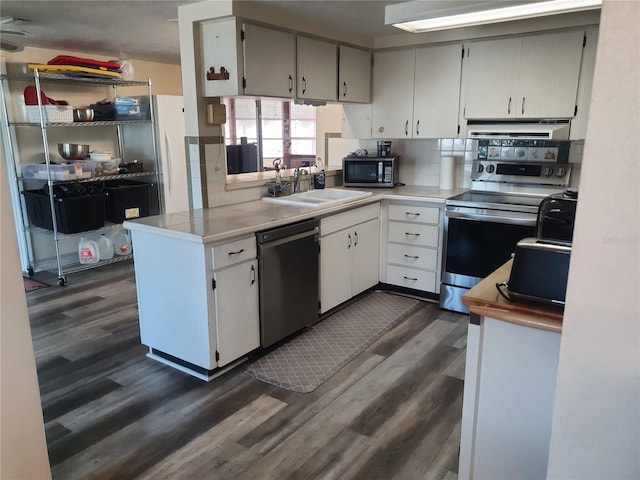 kitchen with sink, dark wood-type flooring, backsplash, stainless steel appliances, and white cabinets