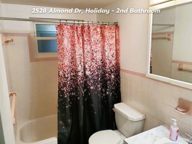 full bathroom featuring vanity, tile walls, shower / bath combination with curtain, and toilet