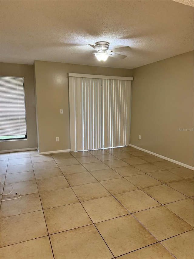 unfurnished room featuring ceiling fan, light tile patterned floors, and a textured ceiling