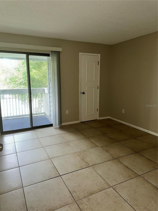 unfurnished room with a textured ceiling and light tile patterned flooring