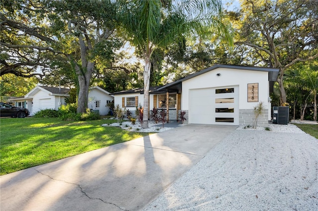 ranch-style home with a front yard, central AC unit, and a garage