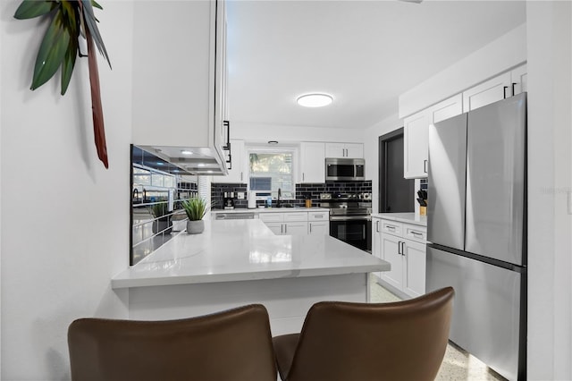 kitchen with a breakfast bar area, appliances with stainless steel finishes, sink, decorative backsplash, and white cabinetry