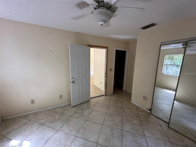 unfurnished bedroom with a textured ceiling, light tile patterned floors, ceiling fan, and a closet