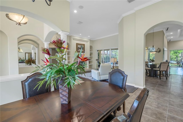 tiled dining room featuring built in shelves, decorative columns, an inviting chandelier, and crown molding