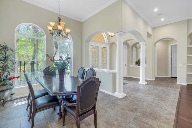 dining room featuring an inviting chandelier, crown molding, light wood-type flooring, decorative columns, and a towering ceiling