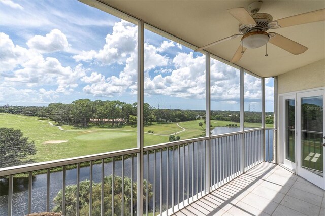 unfurnished sunroom featuring a water view, ceiling fan, and a healthy amount of sunlight