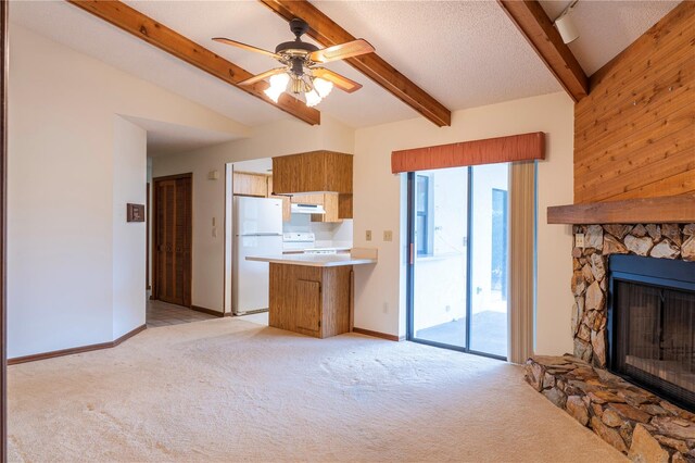 kitchen featuring kitchen peninsula, vaulted ceiling with beams, white appliances, a stone fireplace, and ceiling fan