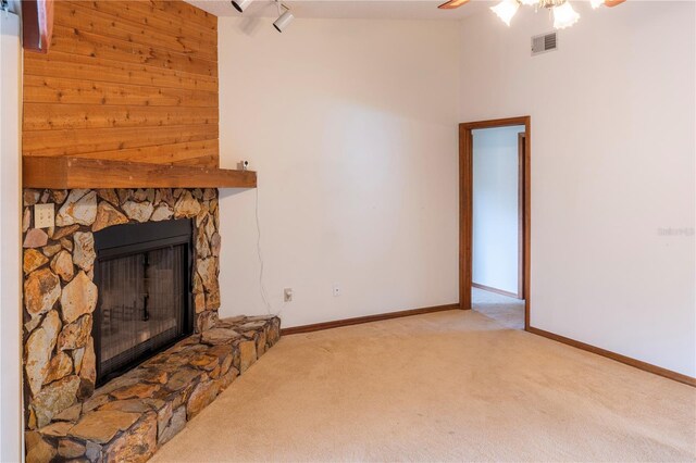 living room with a stone fireplace, vaulted ceiling, ceiling fan, and light colored carpet