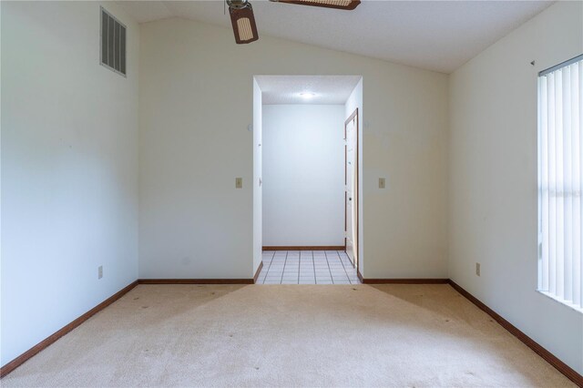 carpeted empty room featuring a textured ceiling, vaulted ceiling, ceiling fan, and a wealth of natural light