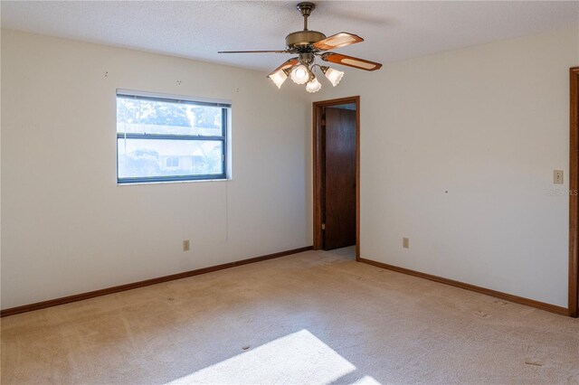 carpeted spare room featuring ceiling fan and a textured ceiling