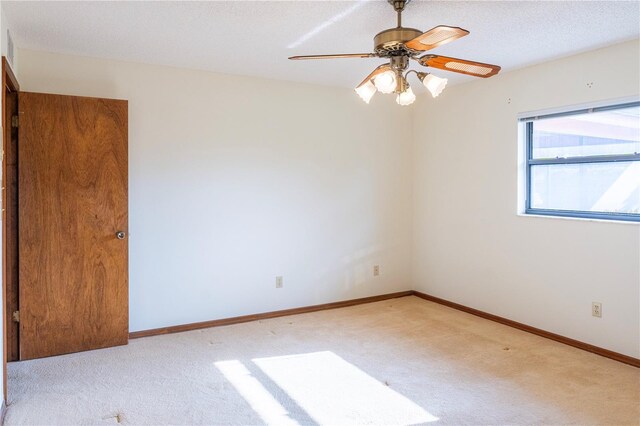 carpeted empty room with ceiling fan and a textured ceiling