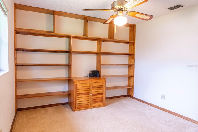 unfurnished office with ceiling fan, light colored carpet, and a textured ceiling