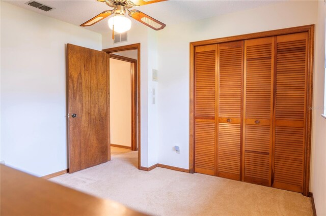 unfurnished bedroom featuring a closet, light colored carpet, and ceiling fan