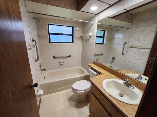 full bathroom featuring tiled shower / bath, vanity, toilet, and a wealth of natural light