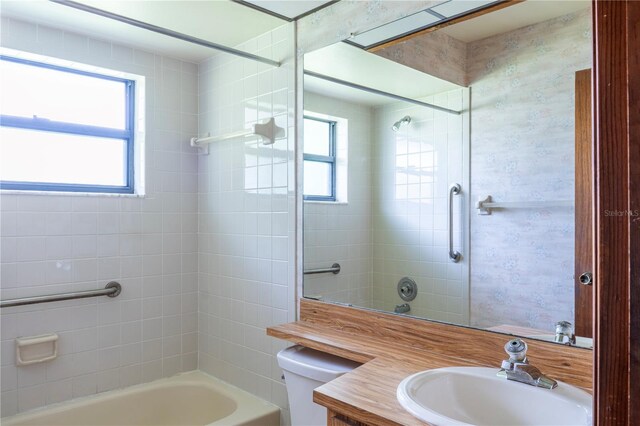 full bathroom with tiled shower / bath, plenty of natural light, vanity, and toilet