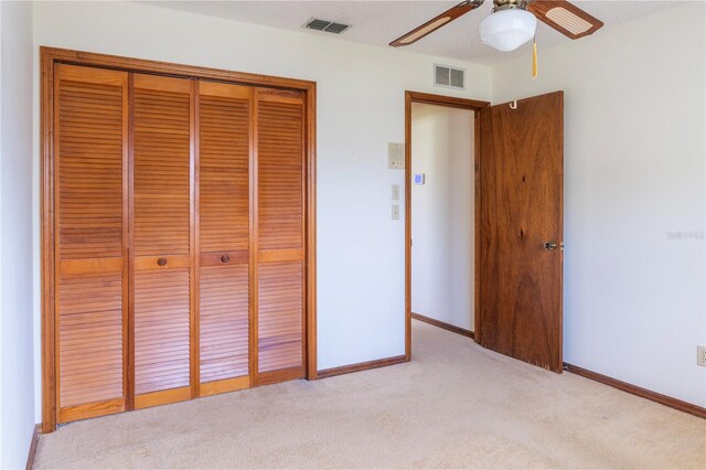 unfurnished bedroom featuring ceiling fan, light colored carpet, a textured ceiling, and a closet