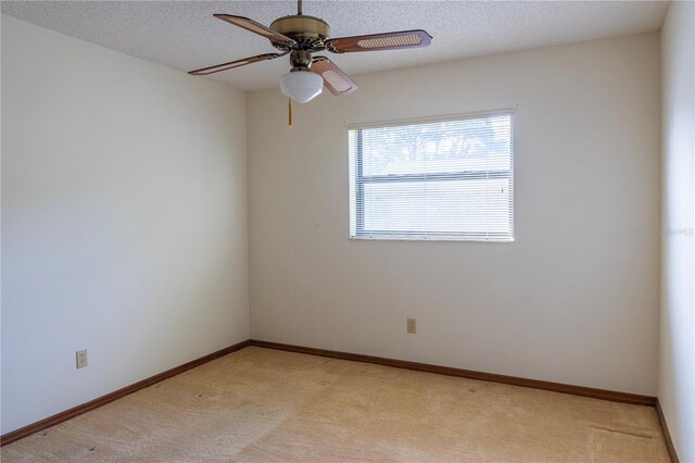 spare room with ceiling fan, a textured ceiling, and light carpet