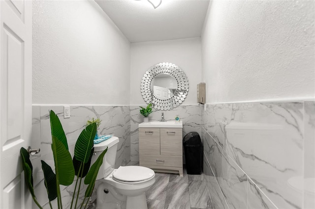 bathroom featuring tile walls, toilet, a textured ceiling, and vanity