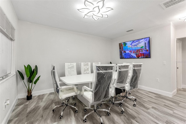 dining space with light wood-type flooring and a textured ceiling