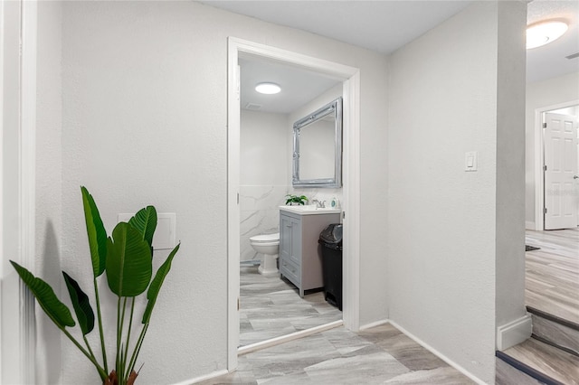 corridor with light wood-type flooring and sink