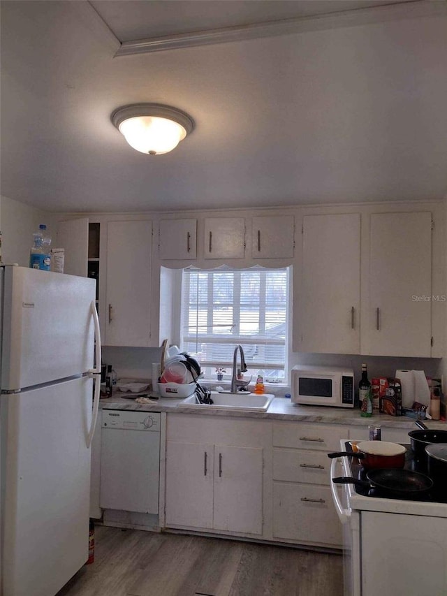 kitchen featuring light wood-type flooring, white appliances, white cabinetry, and sink