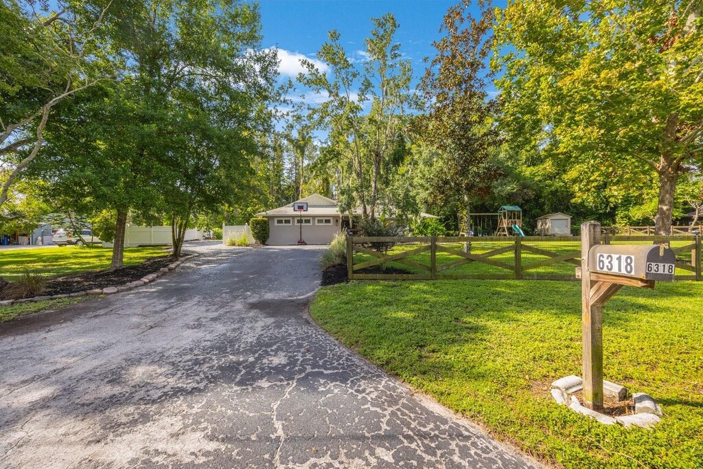 view of front of house featuring a garage, a front yard, an outbuilding, and a playground