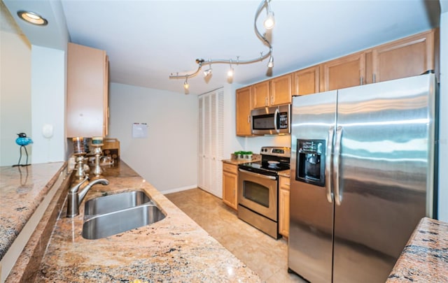 kitchen with light stone counters, sink, and stainless steel appliances