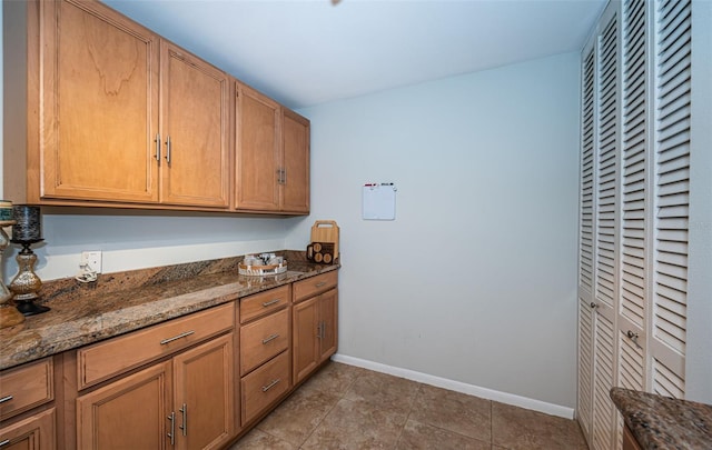 kitchen featuring light tile patterned flooring and dark stone countertops