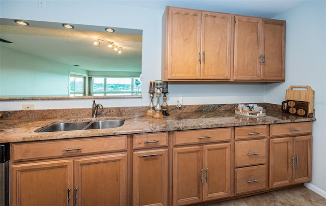 kitchen featuring a textured ceiling, dishwasher, dark stone countertops, and sink