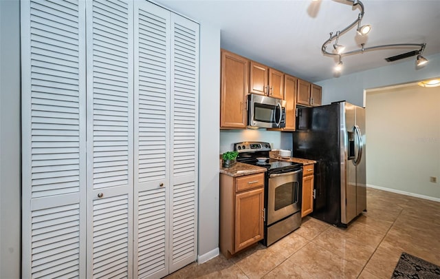 kitchen featuring light tile patterned floors, stainless steel appliances, and dark stone countertops