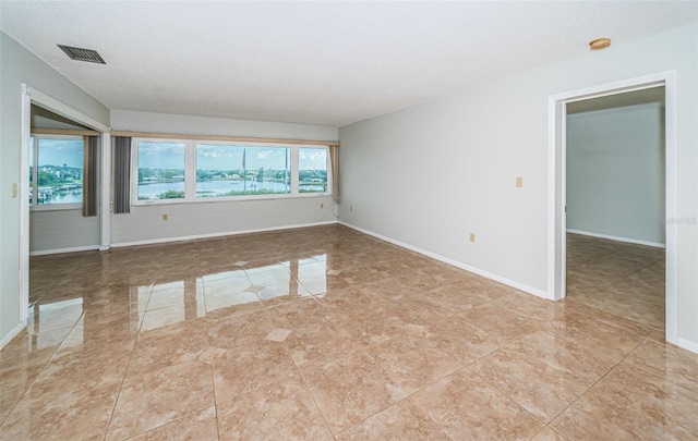 tiled spare room featuring a textured ceiling