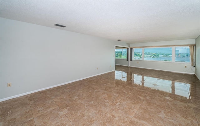 tiled empty room with a textured ceiling