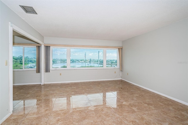 unfurnished room featuring a textured ceiling and a water view