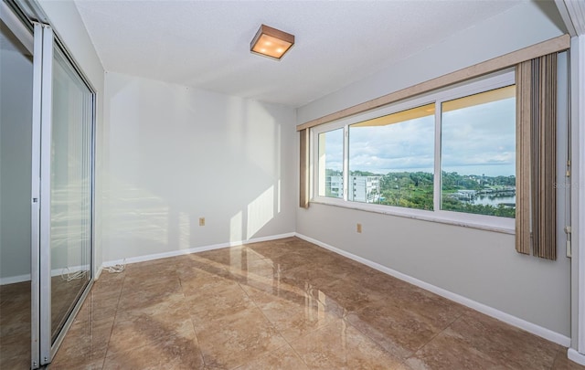 unfurnished bedroom featuring a textured ceiling, a water view, and a closet