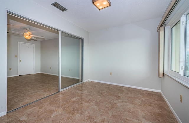 unfurnished bedroom with ceiling fan, a textured ceiling, and a closet