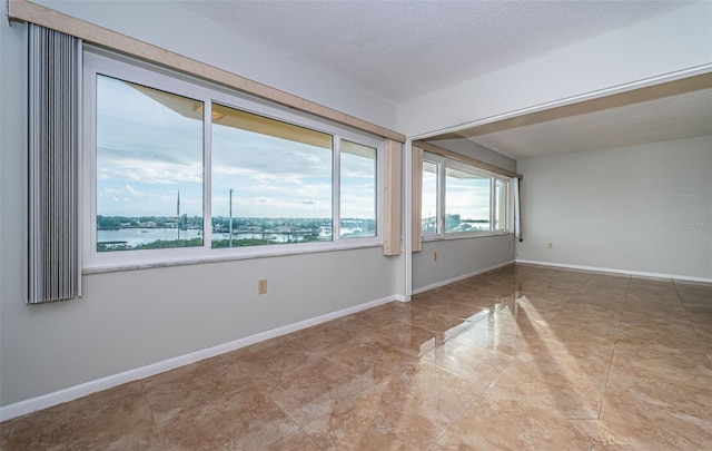 empty room with a water view and a textured ceiling