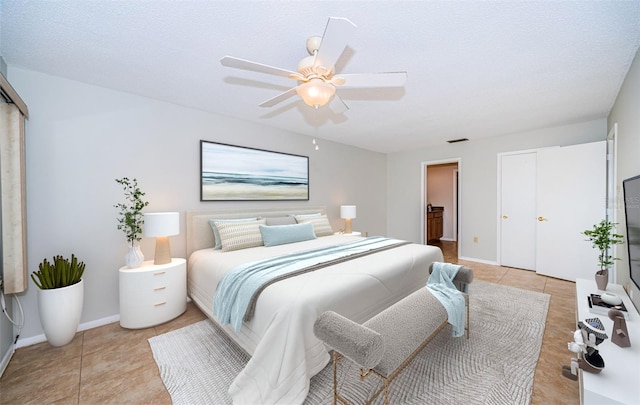 bedroom featuring ceiling fan, light tile patterned flooring, and a textured ceiling