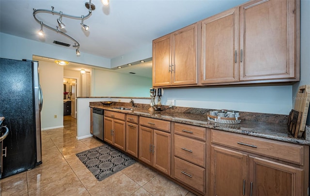 kitchen with dark stone countertops, sink, light tile patterned floors, and stainless steel appliances